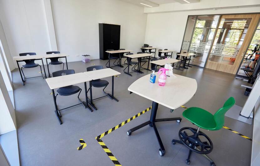 Leeg klaslokaal, tafels en stoelen op 1,5 meter afstand